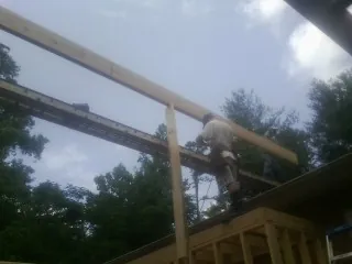 Carpenter setting a ridge beam over a new addition frame — Ice Dam Removal by Roofing Brothers in Glenwood Landing