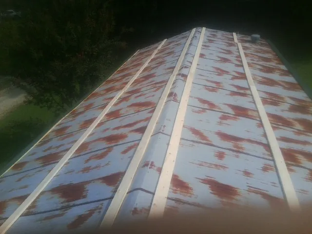 Rusted metal roof panels with new wood purlins before replacement — Storm Damage Roof Repair in Glenwood Landing by Roofing Brothers