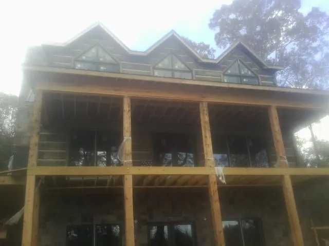 Dormers and porch framing on a large log home under construction — Roof Coating work by our crew in Glenwood Landing