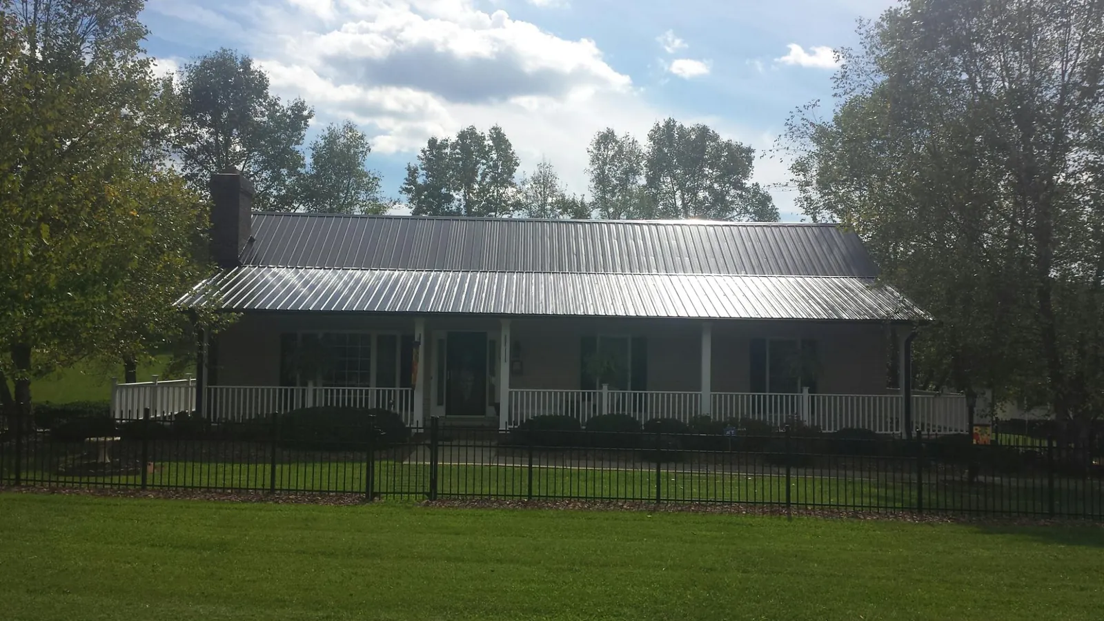 Gray metal roof on a brick ranch with a full width front porch — Gutter Guard Installation work by our crew in Glenwood Landing