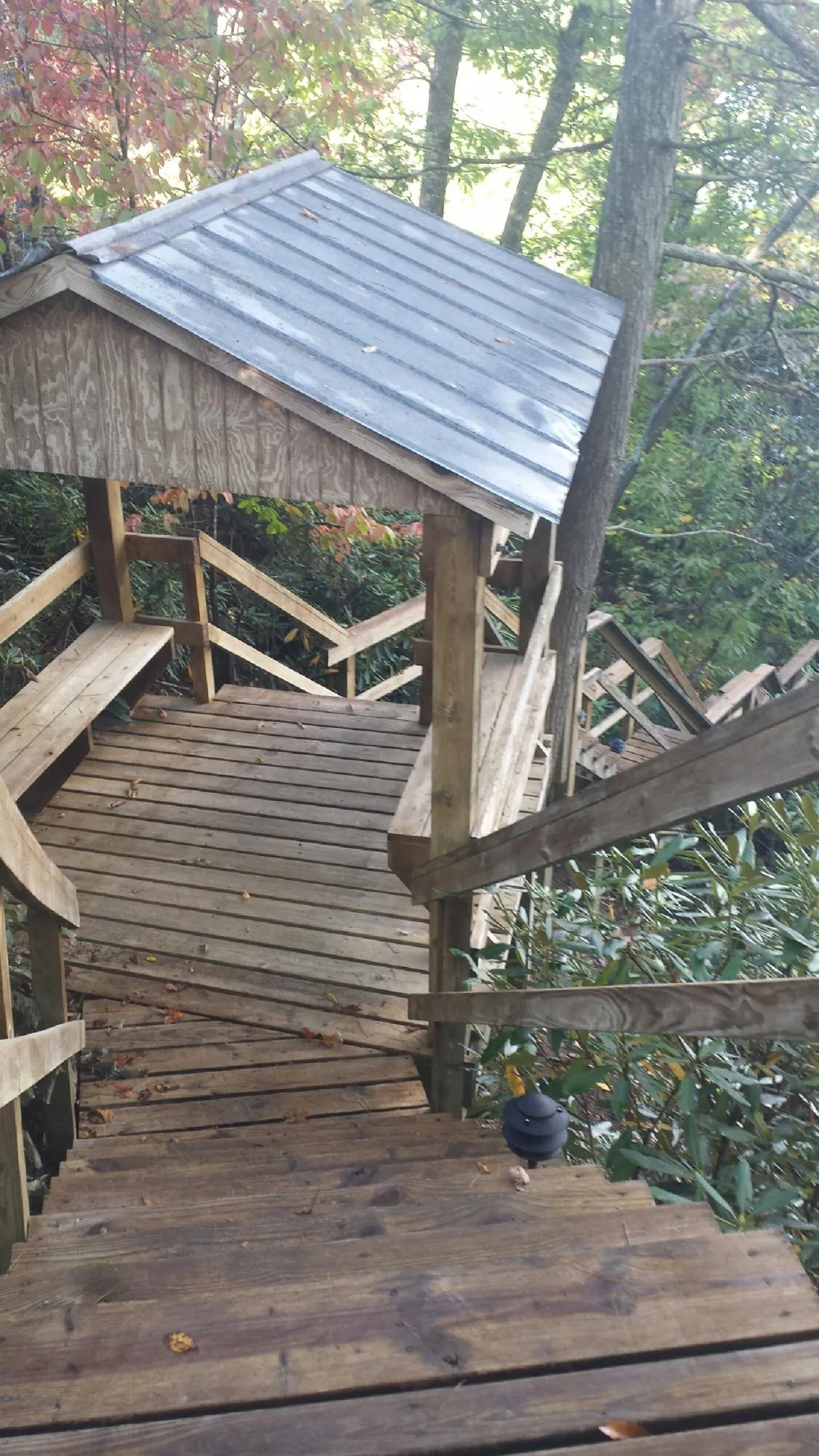 Metal roofed shelter over wooden steps on a wooded walkway — Skylight Repair & Installation work by our crew in Glenwood Landing