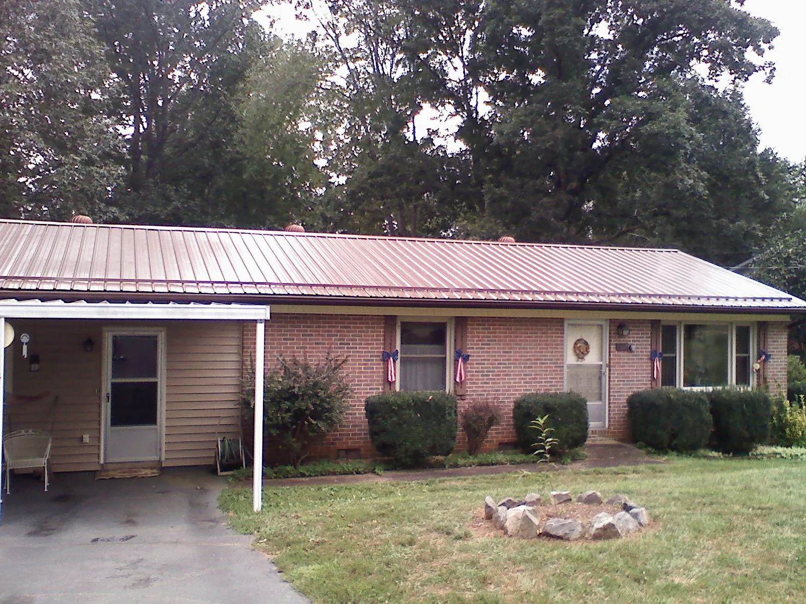 Bronze metal roof and carport on a brick ranch home — Roof Repair work by our crew in Glenwood Landing